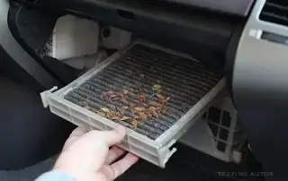 hand pulling out a dirty cabin filter from car