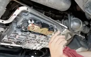 person checking transmission fluid under vehicle